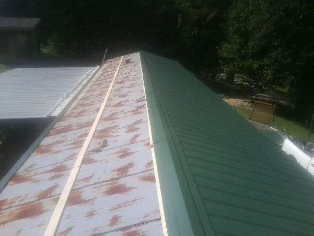 Old rusted panels beside newly installed green metal roofing — Wind Damage Roof Repair by Roofing Brothers in Minden