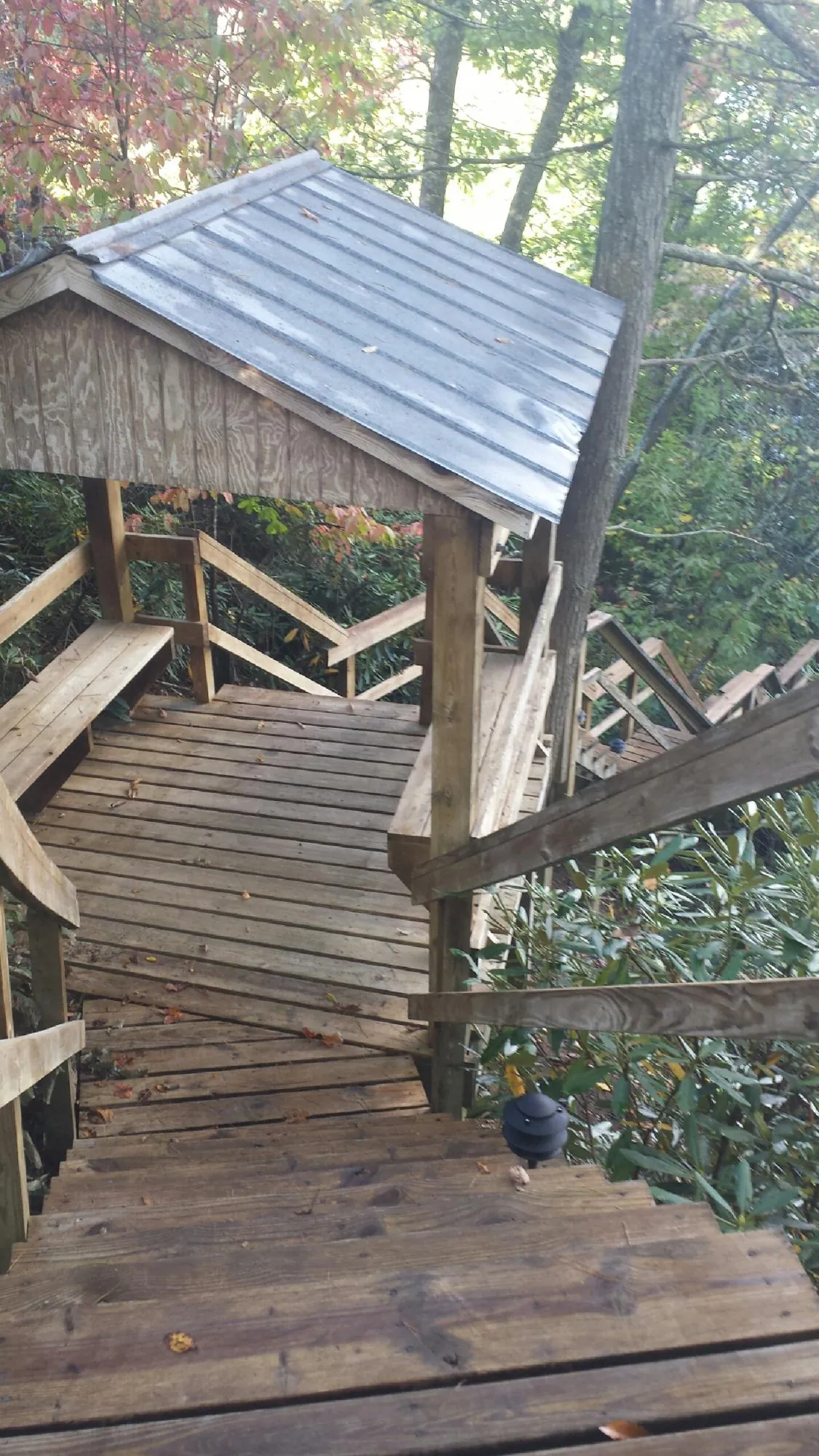 Metal roofed shelter over wooden steps on a wooded walkway — Skylight Repair & Installation work by our crew in Minden