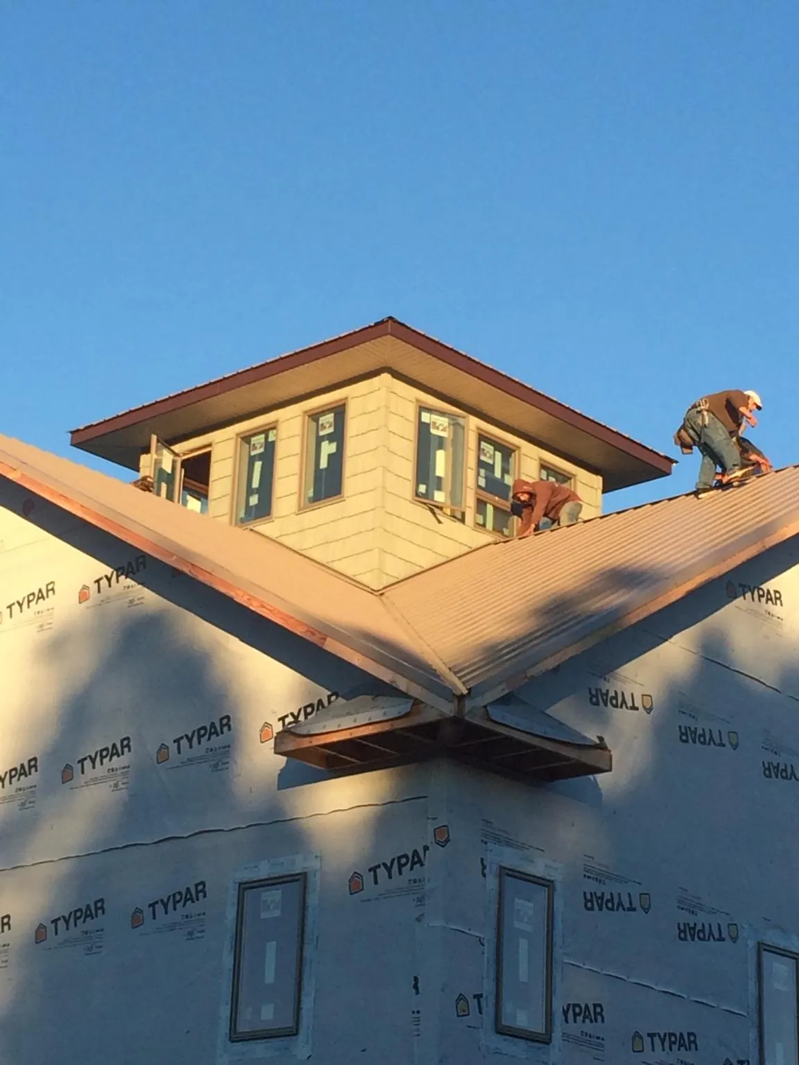 Roofers working around a rooftop cupola on a new metal roof at sunset — Roof Waterproofing in Minden by Roofing Brothers